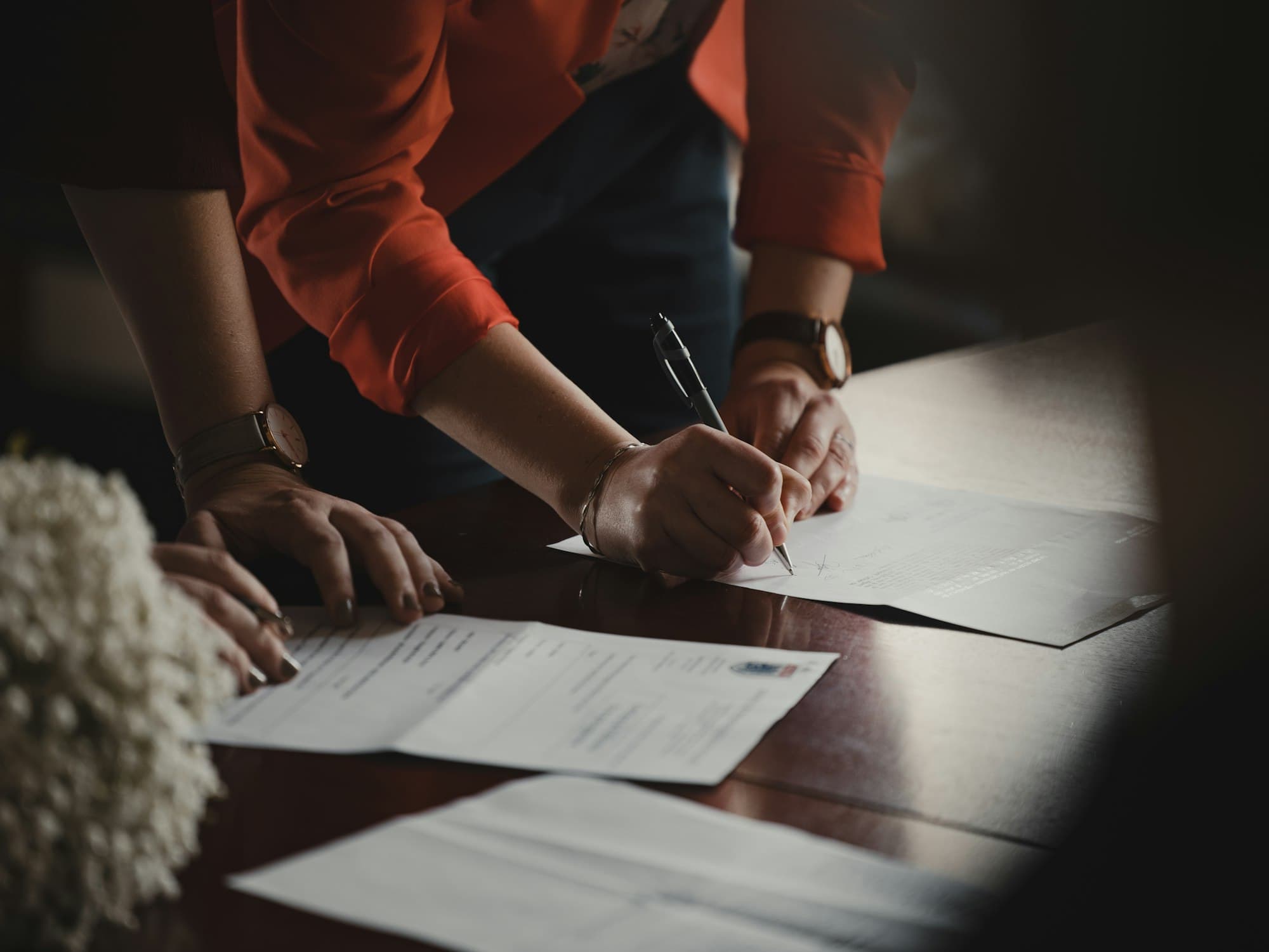 A person signing a document at a desk